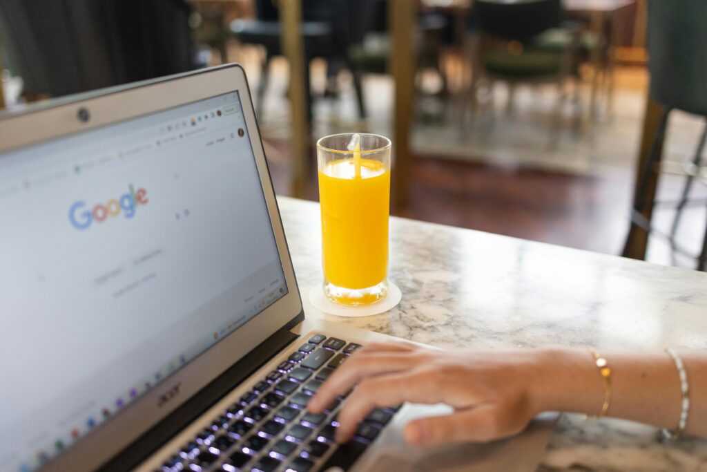 Woman Using a Computer Laptop Near a Glass of Juice